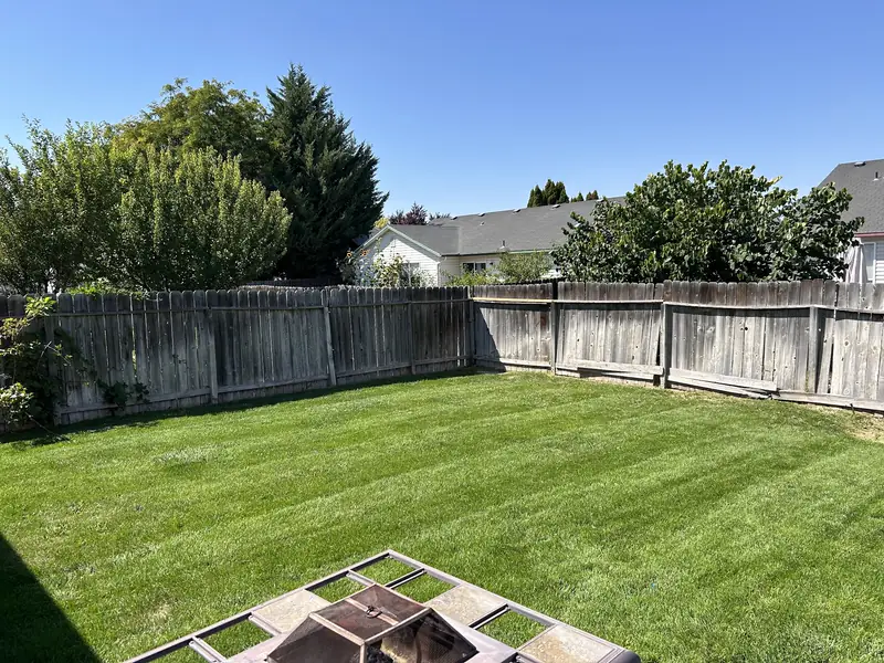 A fenced backyard with a mowed lawn